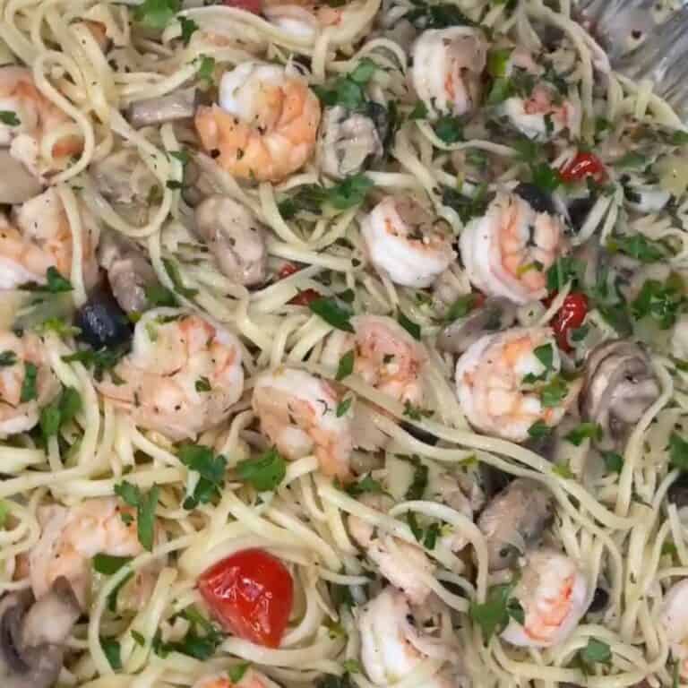 Spaghetti pasta mixed with shrimp, sliced mushrooms, cherry tomatoes, and chopped fresh parsley, all coated in a light sauce.