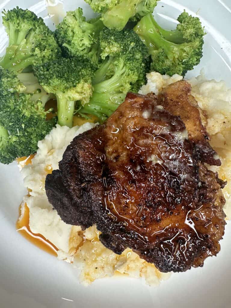 Enjoy easy weeknight juicy chicken thighs, perfectly roasted and served on mashed potatoes with pan juices, alongside steamed broccoli.