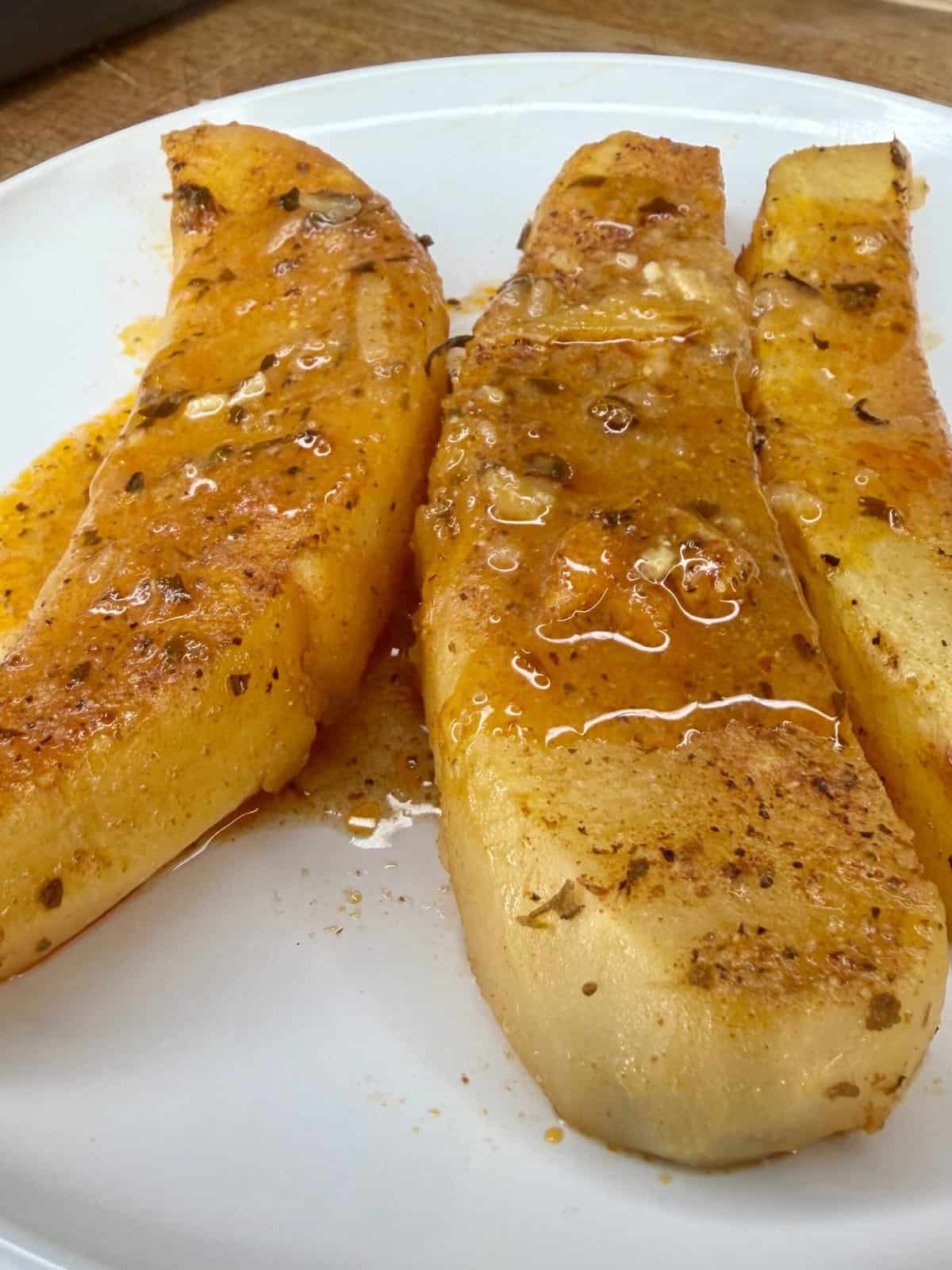 Three slices of ripe papaya on a white plate, topped with chili powder, lime juice, and drizzled with chili sauce for a spicy and tangy twist—perfect alongside Greek Restaurant-Style Lemon Roasted Potatoes.