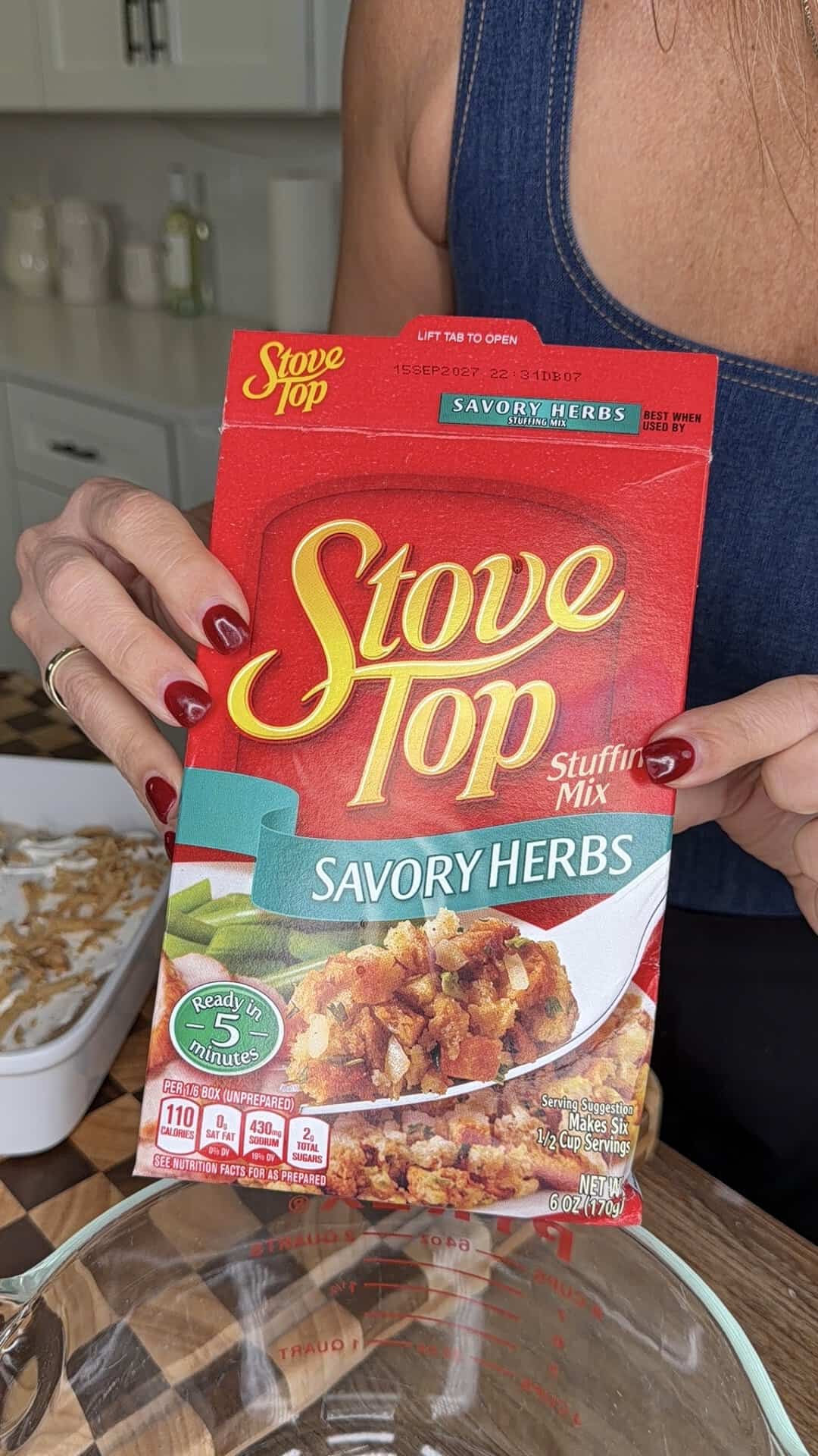 A person holding a box of Stove Top Savory Herbs stuffing mix.