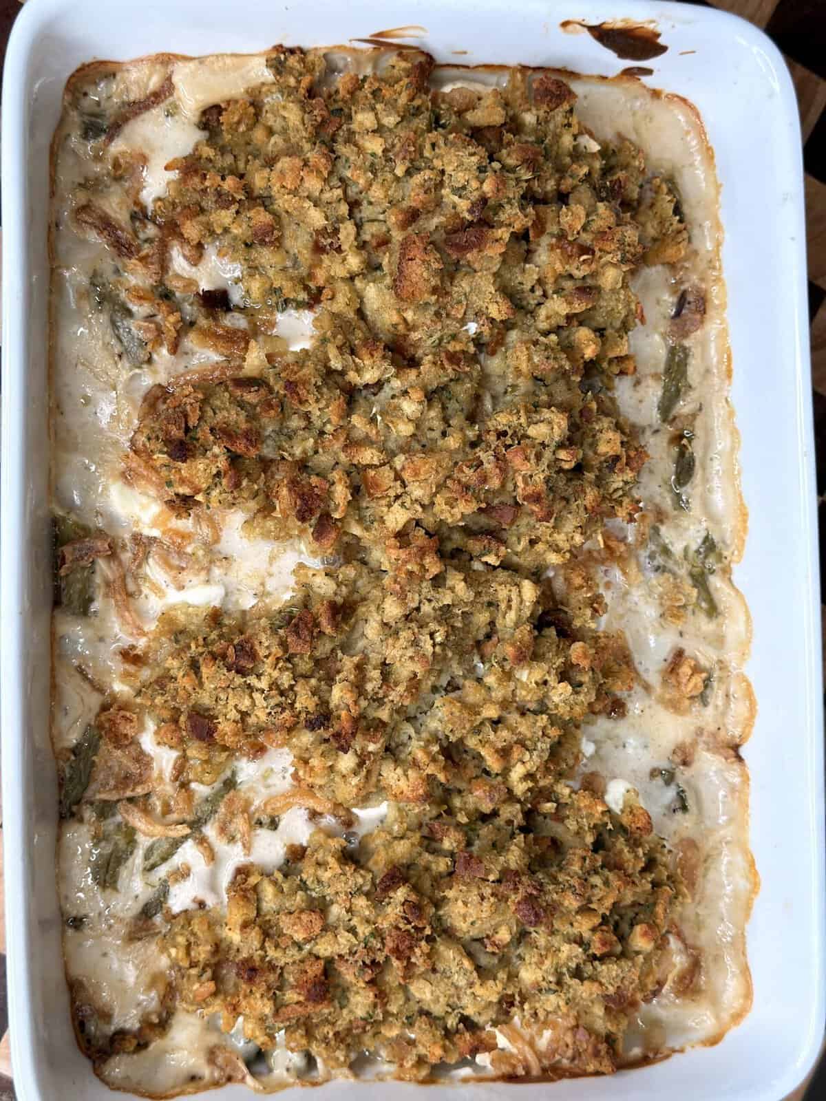 Green bean casserole in a white rectangular baking dish, topped with a browned breadcrumb crust.