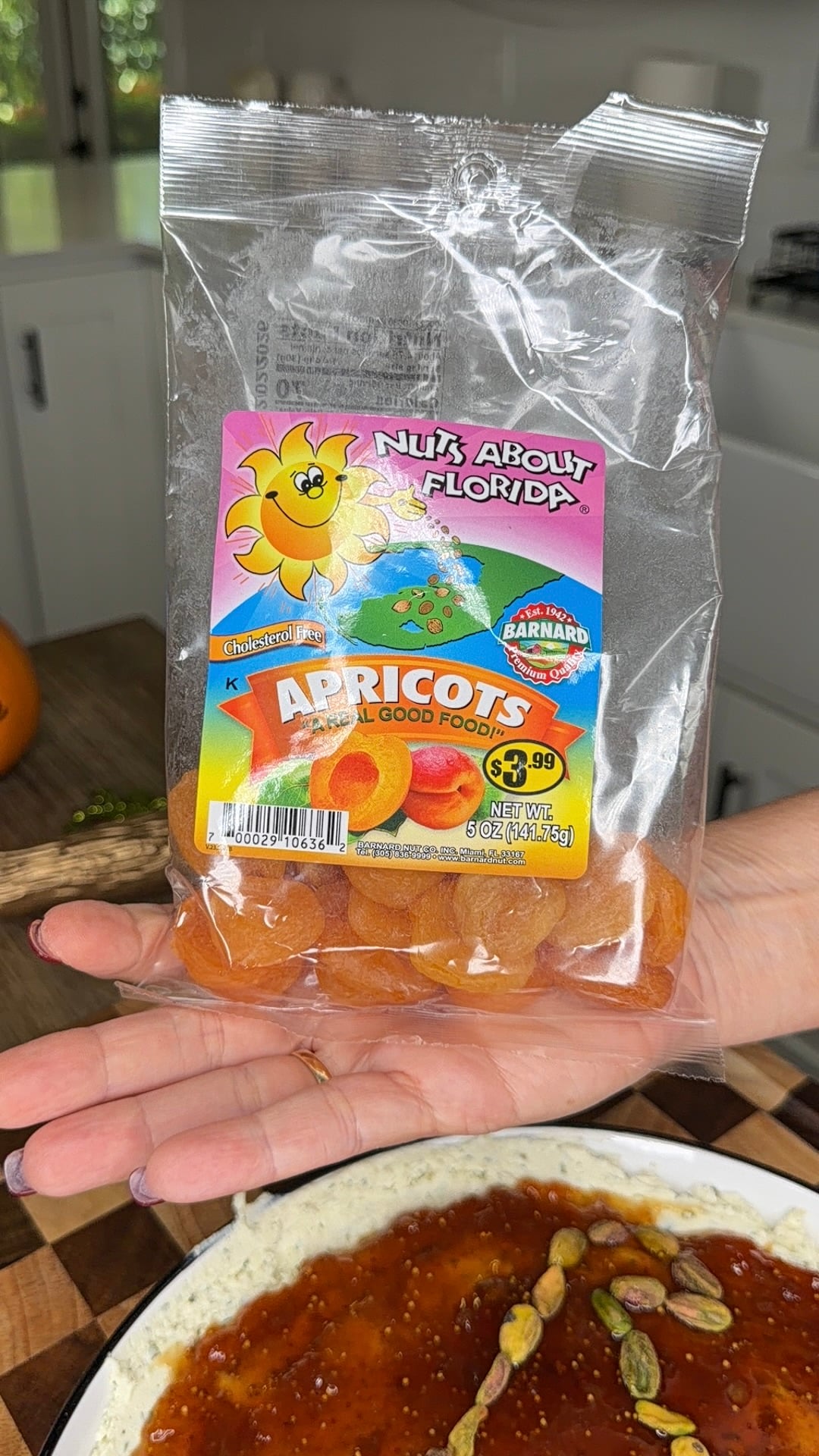 A hand holds a 5-ounce bag of Nuts About Florida dried apricots.