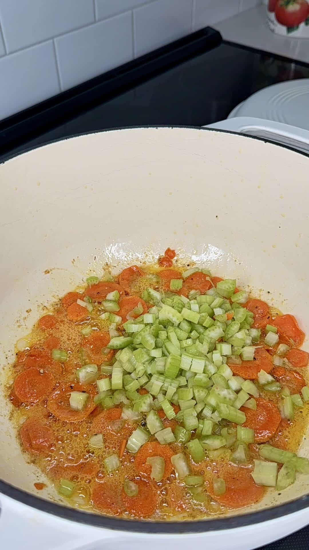 Sliced carrots and chopped celery sautéing in a pan with butter.