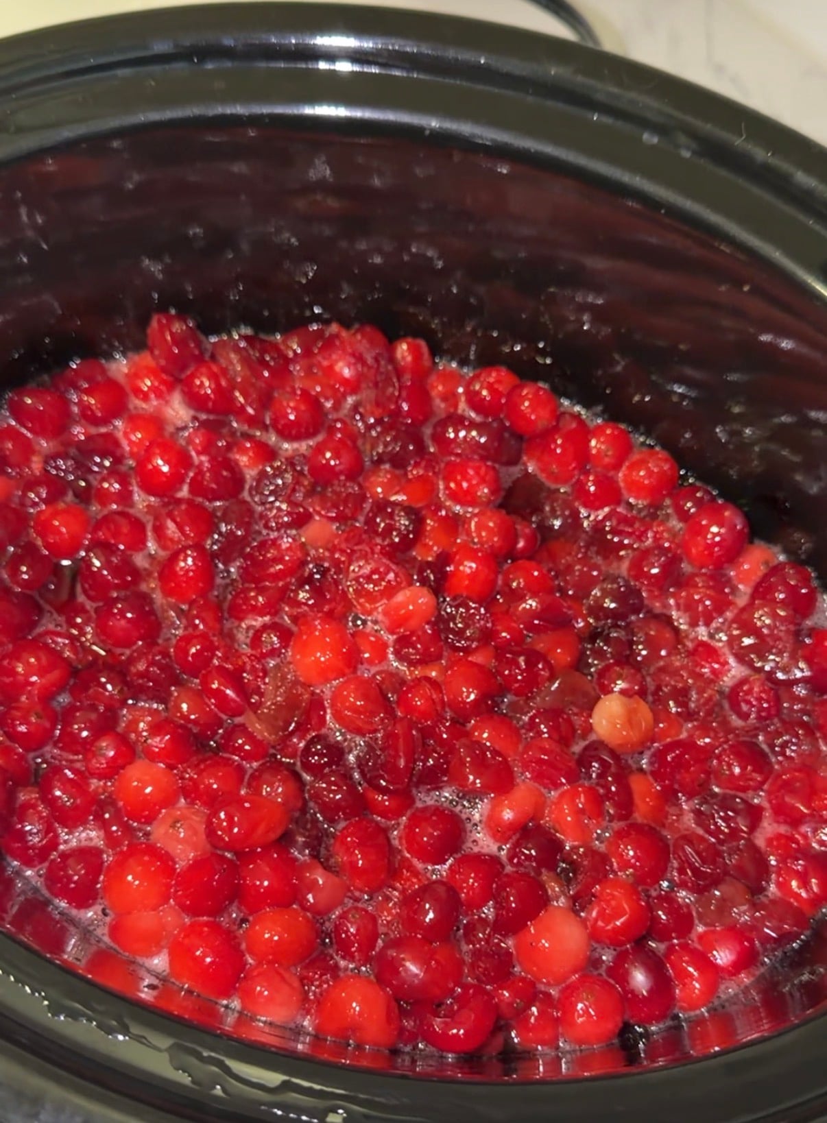 Fresh cranberries cooking in a slow cooker.