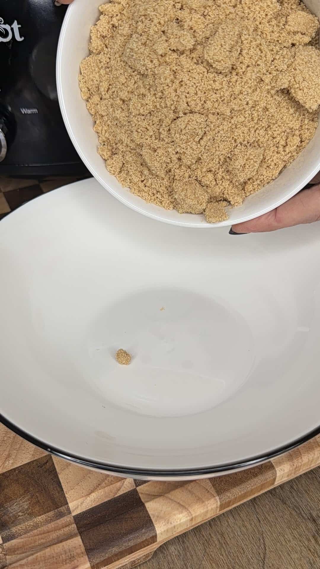 Hands pouring a bowl of brown sugar into a large empty mixing bowl.