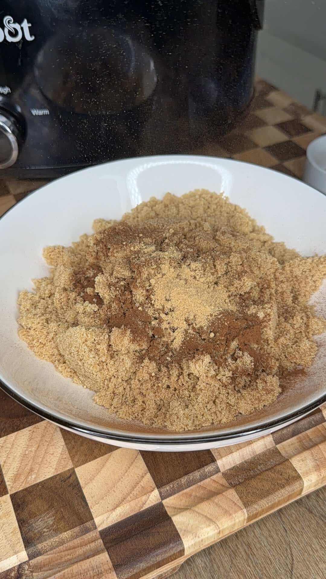 A white bowl filled with brown sugar topped with a mound of ground cinnamon.