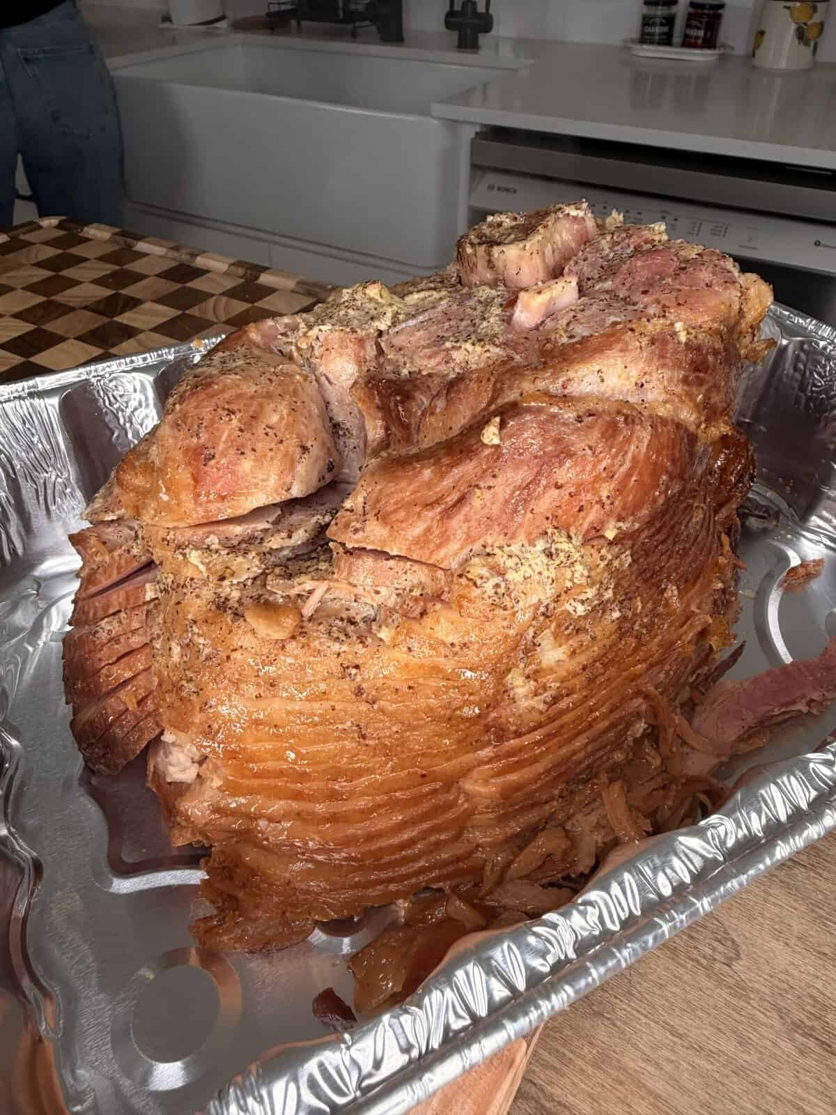 A spiral-cut glazed ham sitting in a foil roasting pan.