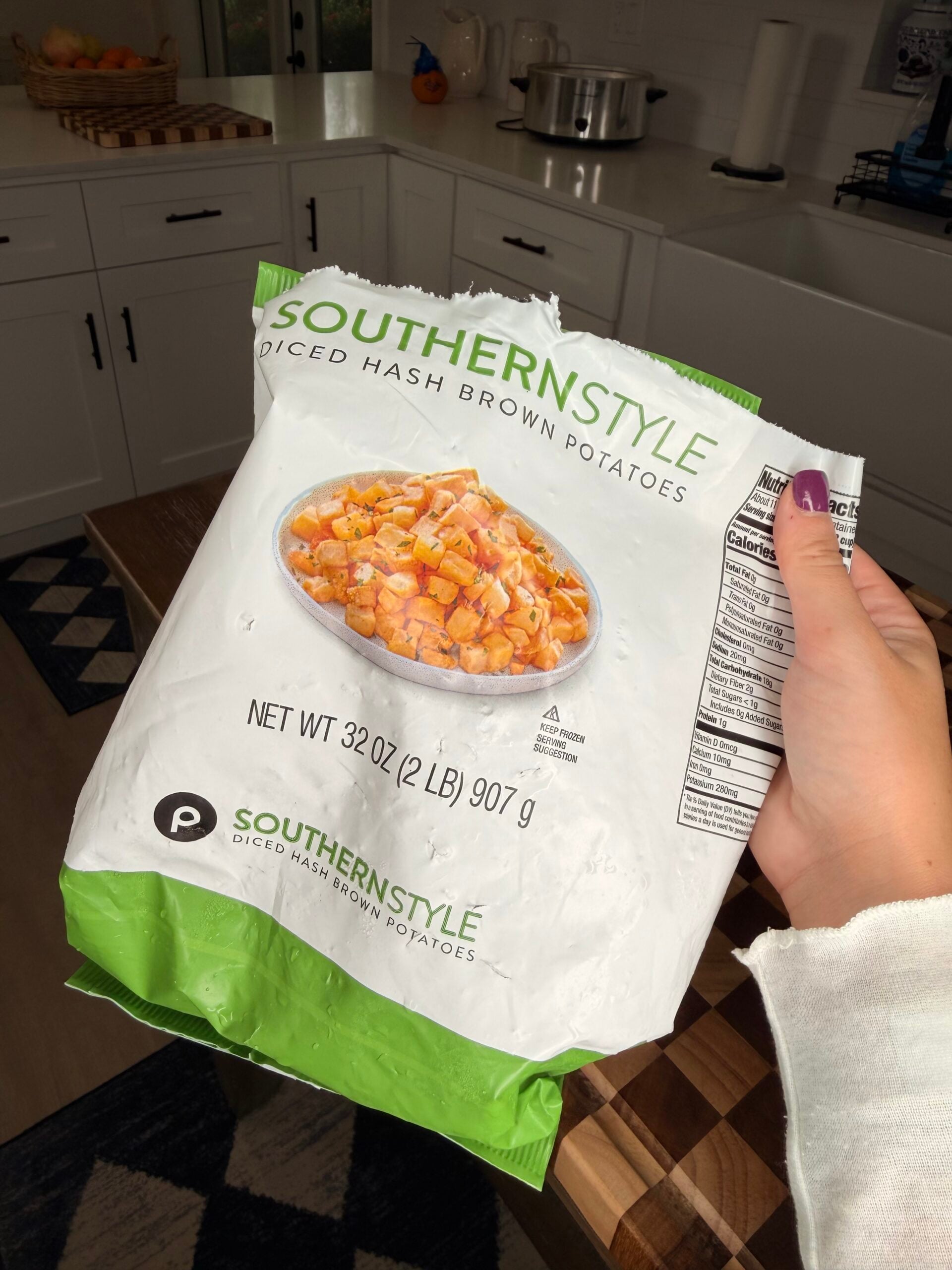 A hand holding a 32-ounce bag of Southern Style diced hash brown potatoes.