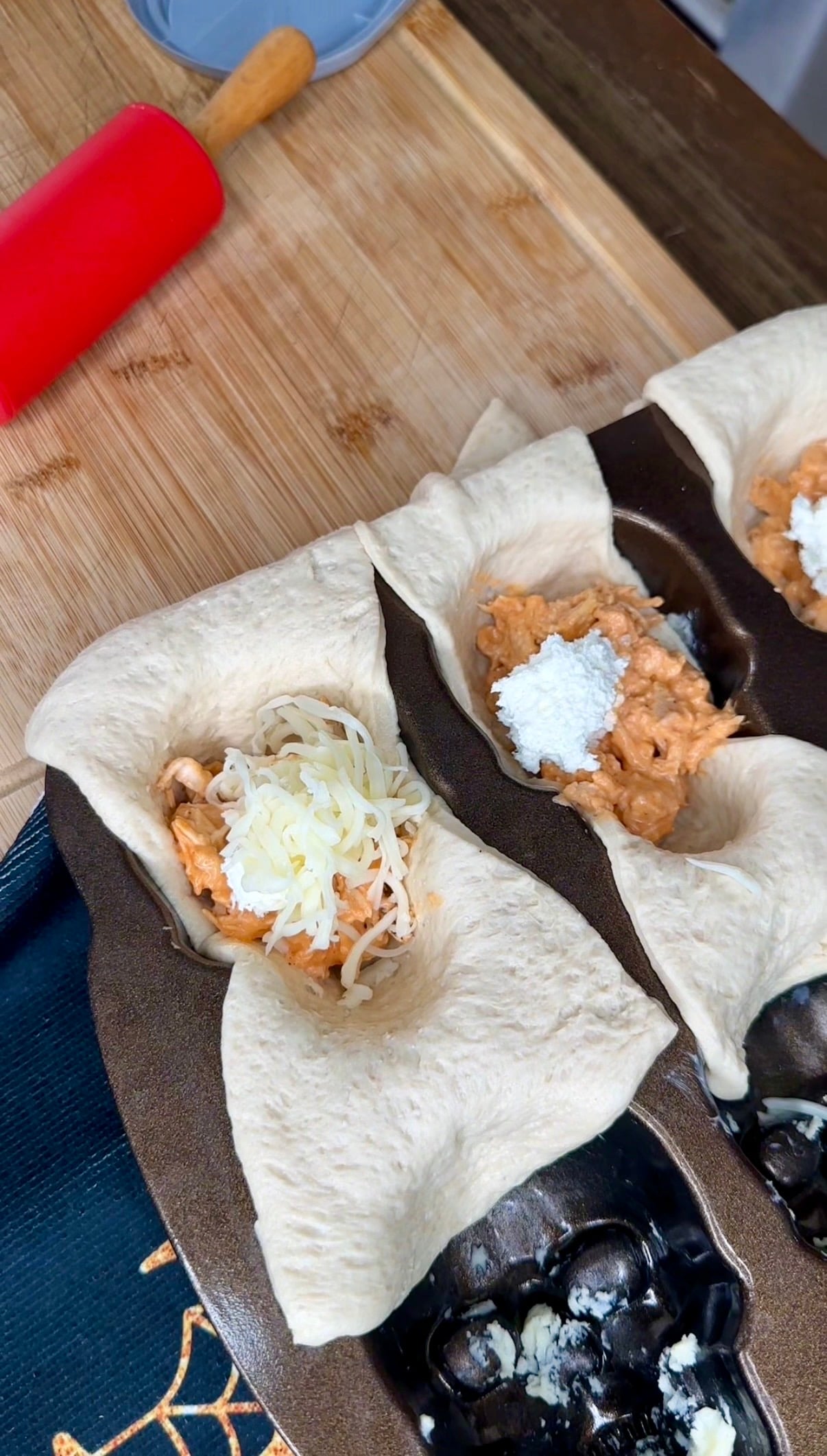 Unbaked dough in a muffin tin filled with shredded chicken and topped with shredded cheese.