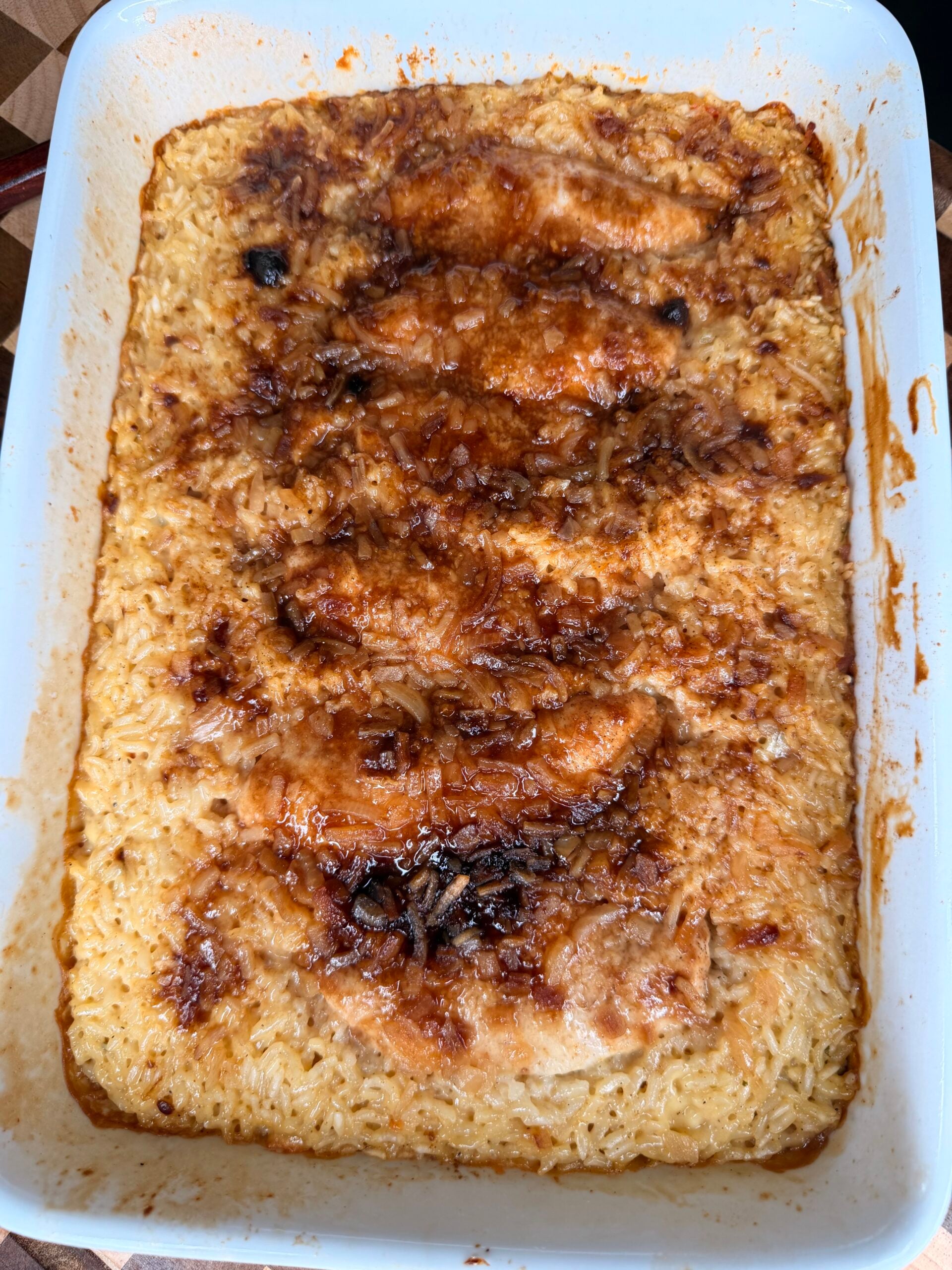 Baked chicken and rice casserole in a rectangular white baking dish.